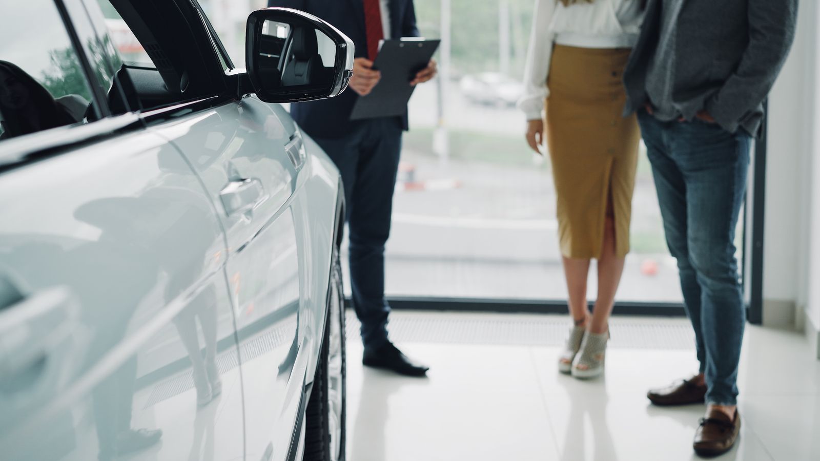 Customers talking with a salesperson at a car dealership
